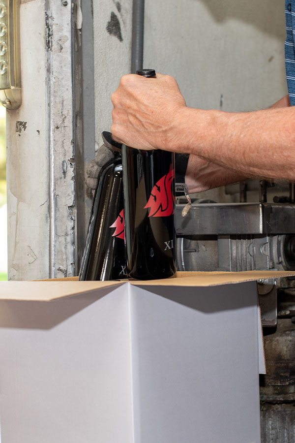 Packing black bottles into a cardboard box
