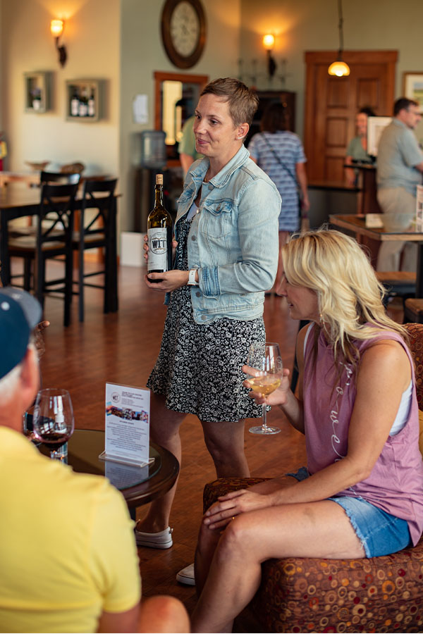 Woman presenting wine in tasting room.