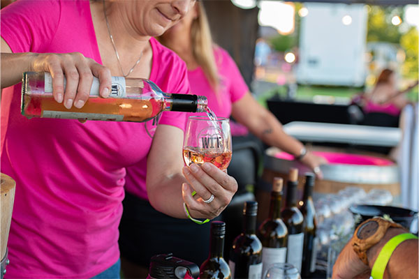 Person pouring wine at outdoor event.