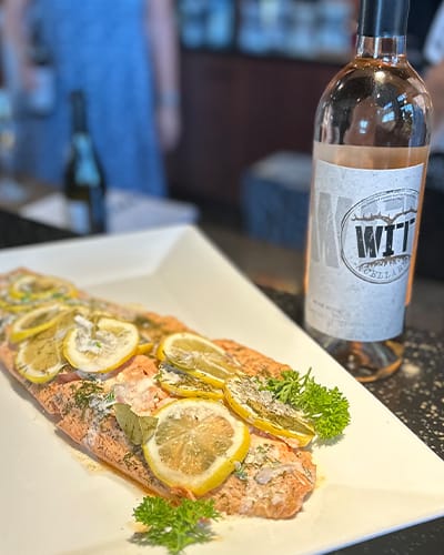 Lemon herb salmon with wine on table