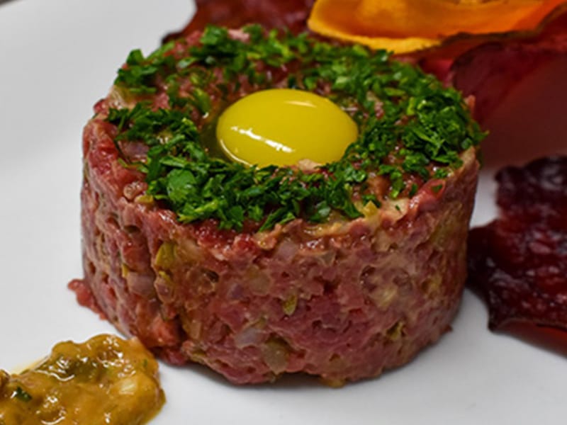 Steak tartare with raw egg yolk and garnish.