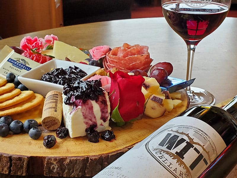Cheese platter with wine and crackers on table.
