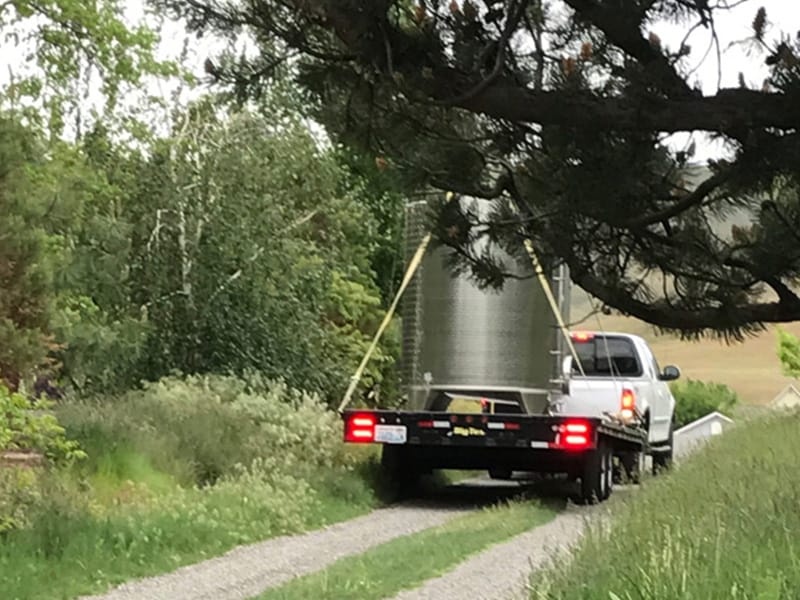 Truck hauling tank on rural road