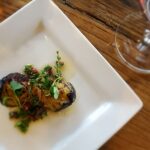 Grilled eggplant dish with herbs on white plate.