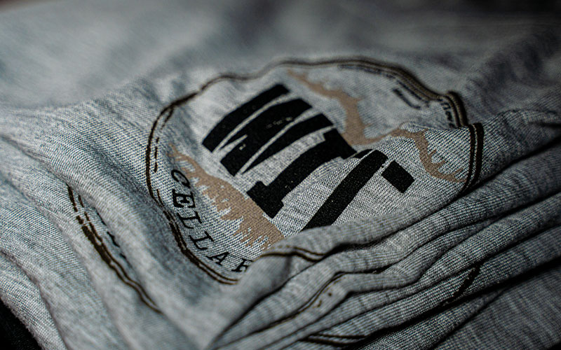 WIT Merch_0012_WIT_Product Lifestyle Shoot_11.23.2021-02587 Gray shirt with black logo design.