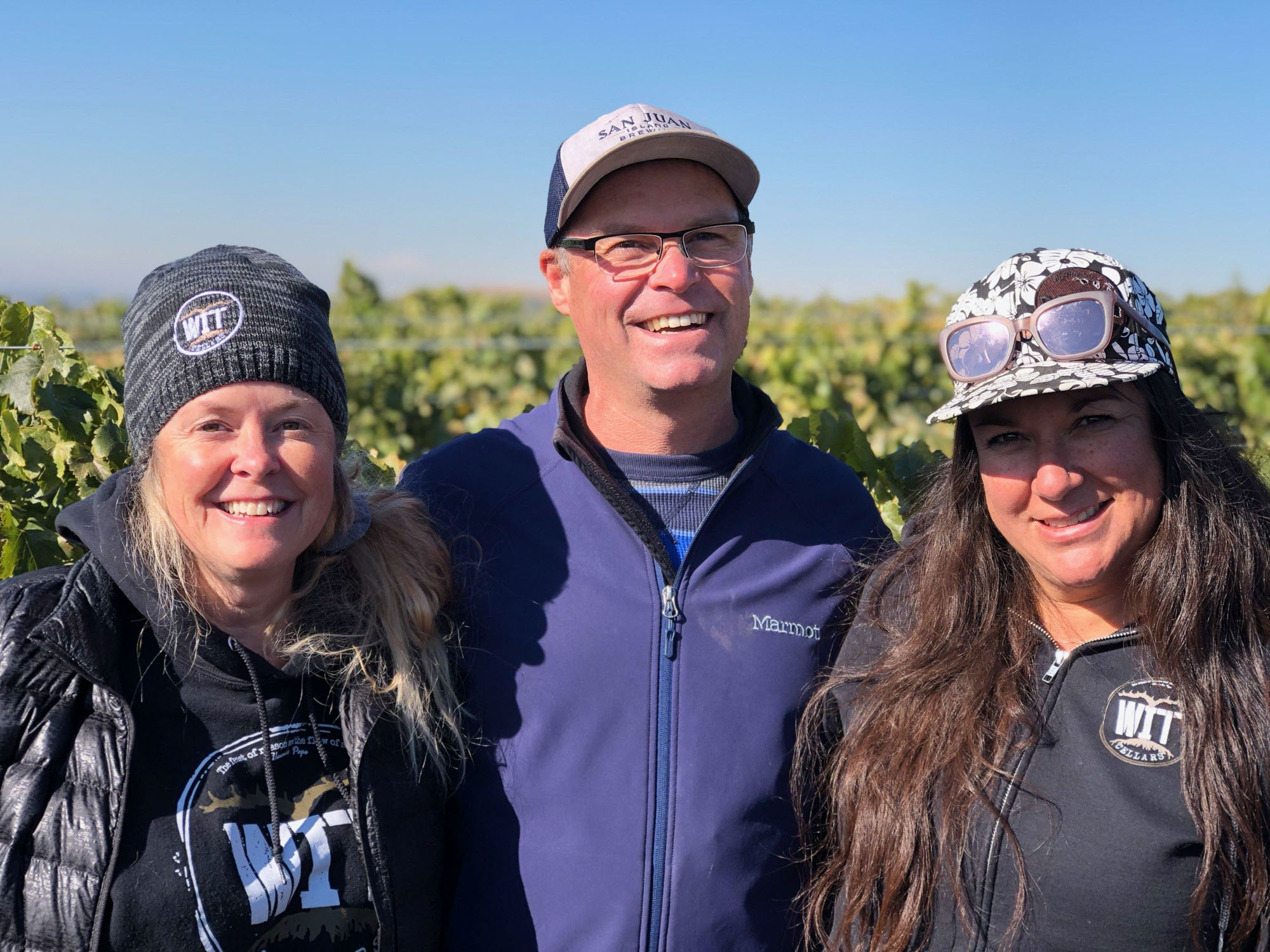WIT crew Three people smiling in a vineyard.
