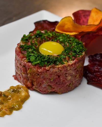 Gourmet steak tartare with egg yolk and herbs.