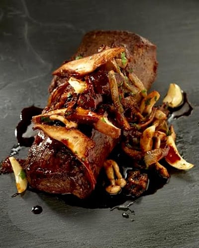 Juicy steak with mushrooms and sauce on plate.