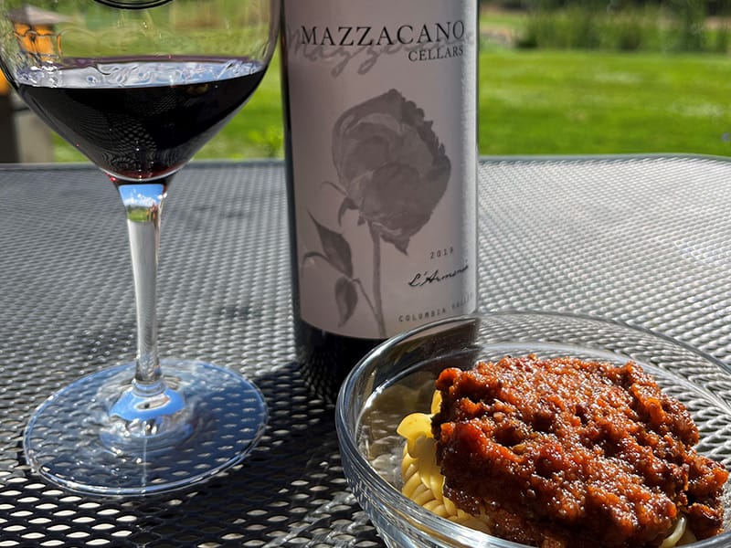 Wine with pasta under sunlight on a table.