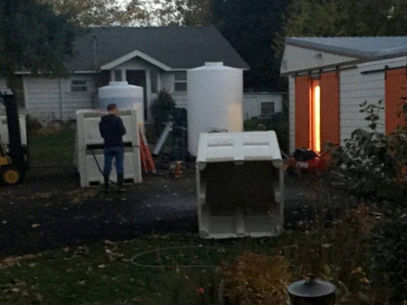 Person working with large white containers outside.