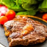 Juicy grilled steak with fresh vegetables on plate.