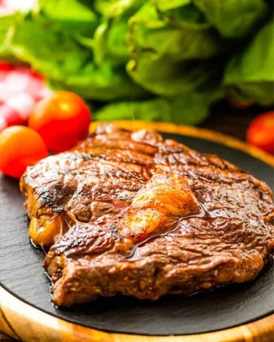 Juicy grilled steak with fresh vegetables on plate.