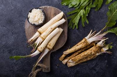 Horseradish Fresh horseradish roots on wooden board with leaves.