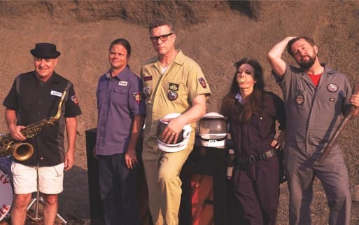 Five people in work uniforms, one with saxophone.