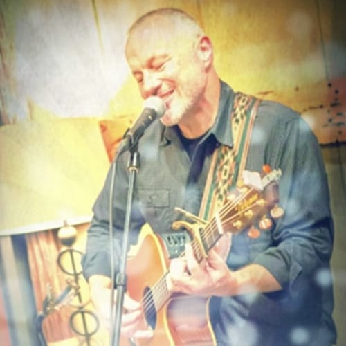 Musician singing and playing guitar on stage.