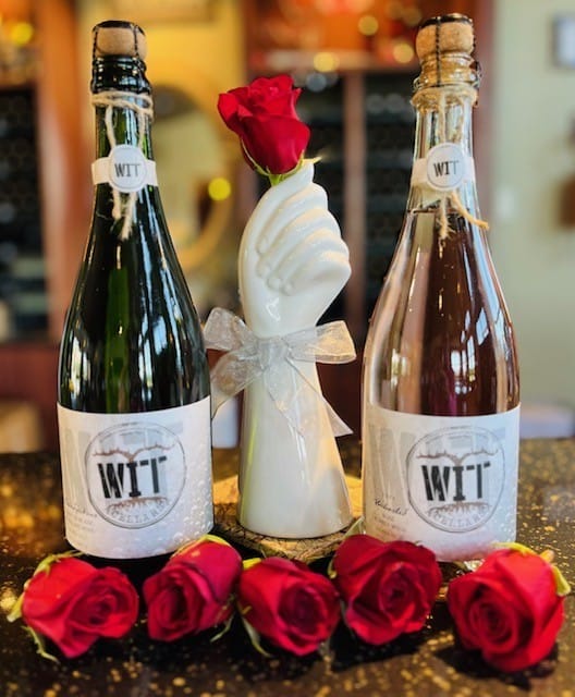 Wine bottles, decorative vase, and red roses
