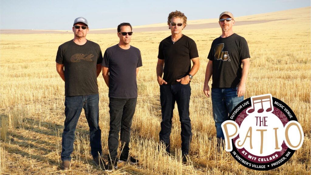Band standing in wheat field under blue sky.