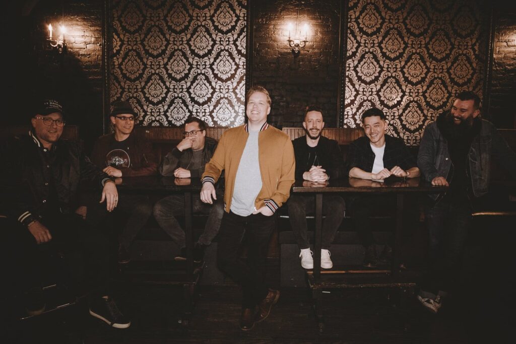 West-Coast-Feed Group of people in a stylish room, smiling.