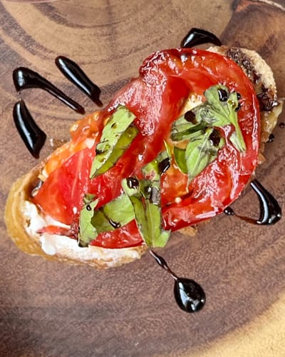 Tomato bruschetta with balsamic glaze and basil leaves.