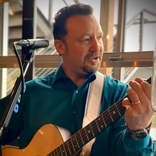 Man playing guitar and singing into microphone.