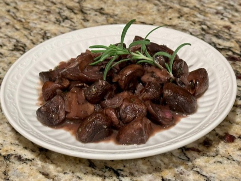 Sautéed mushrooms with rosemary on white plate