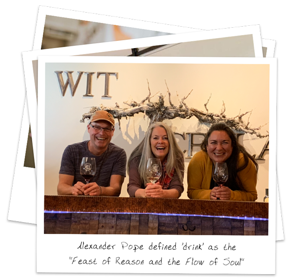 Three smiling adults holding wine glasses at a tasting bar