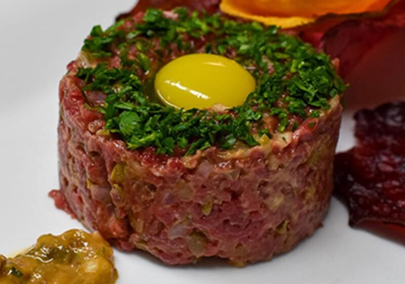 Steak tartare with raw egg yolk and garnish.