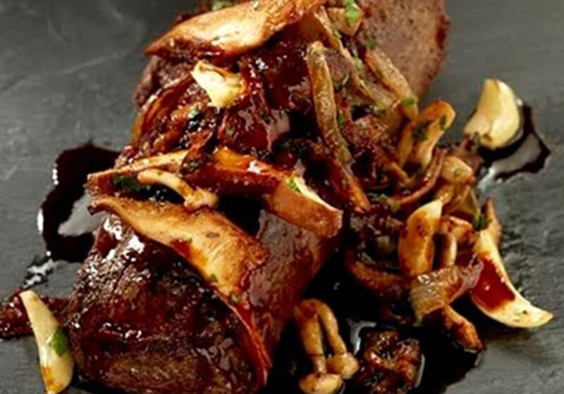 Grilled steak topped with mushrooms and onions.