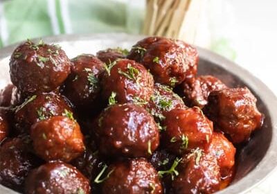 Crockpot-Meatballs Plate of glazed meatballs garnished with herbs.
