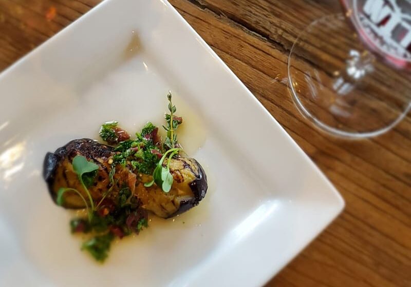 Grilled eggplant dish with herbs on white plate.