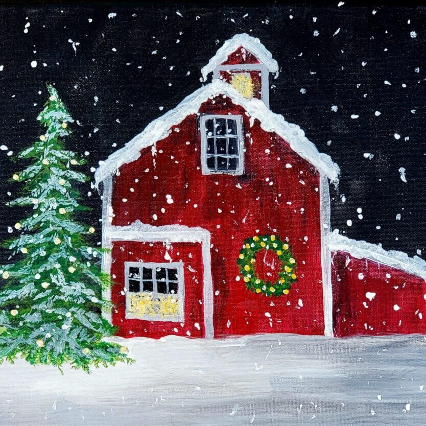 Snowy red barn with Christmas wreath and tree.