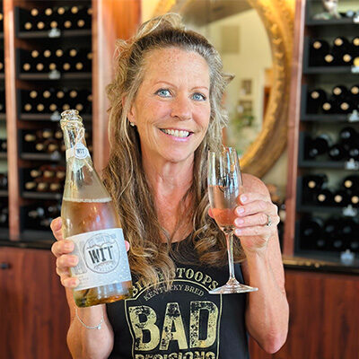 Woman holding wine and glass inside a winery.