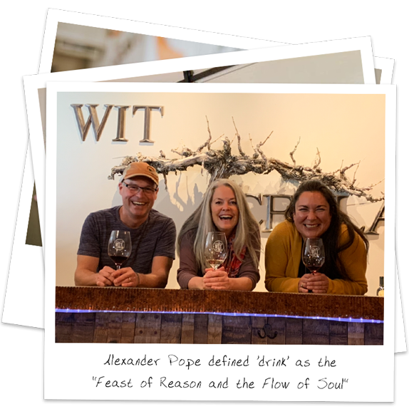 Three smiling adults holding wine glasses at a tasting bar