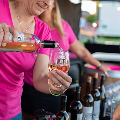Person pouring wine at outdoor event.