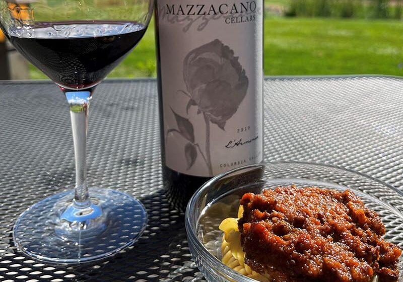 Wine with pasta under sunlight on a table.