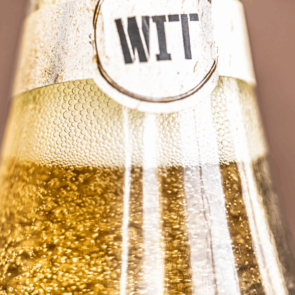 Close-up of beer bottle labeled 'WIT' with bubbles.