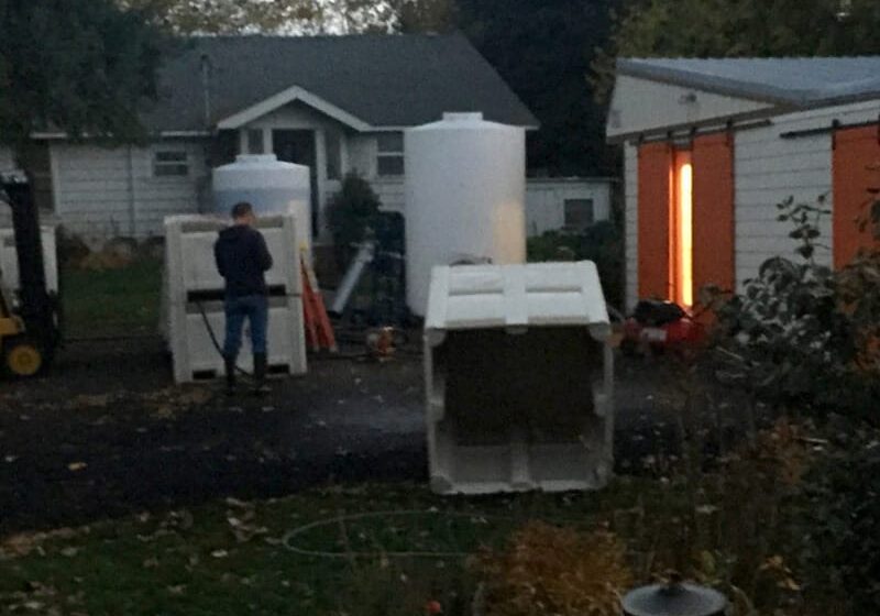 Person working with large white containers outside.