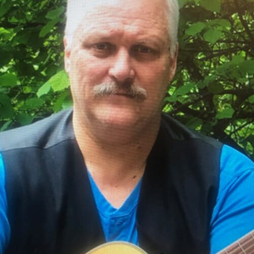 Man with guitar outdoors.